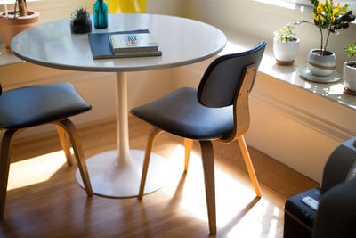棕色硬木地板上两把椅子旁的白色圆餐桌